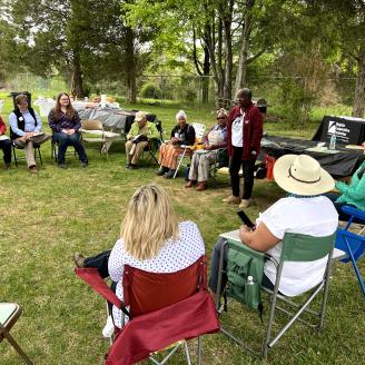 A group of people sitting outdoors at an outreach event hosted by Africulture.