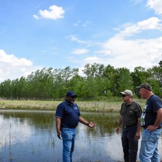 Indiana NRCS State Conservationist Jerry Raynor (left), Leapfrog LLC owner Mark Magura and neighbor Frank Bottos discuss the macros on the property as part of the WRE program. (Indiana NRCS photo by Carly Whitmore)