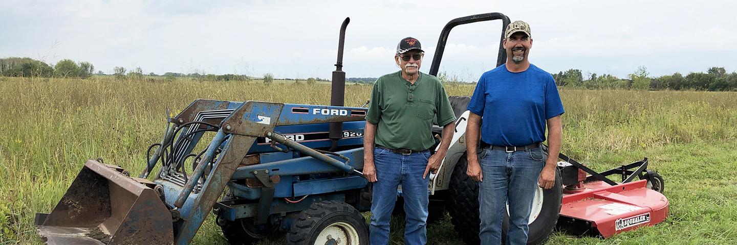 Two men stand in wildlife habitat-friendly land in Fayette County, Iowa