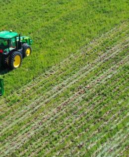 Tractor planting cover crops in a green field.