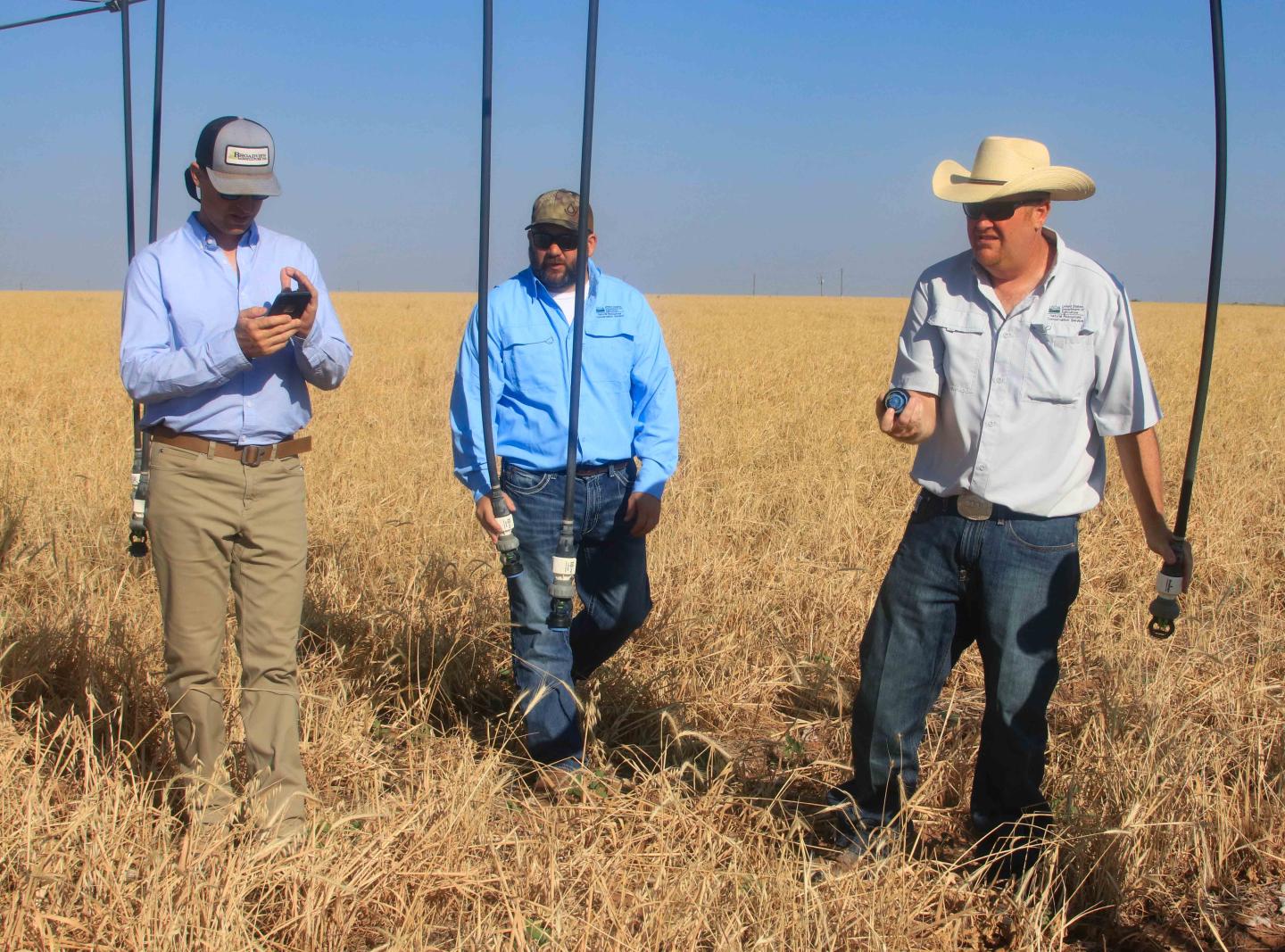 Jeremy Brown visits with NRCS personnel in his crop field.