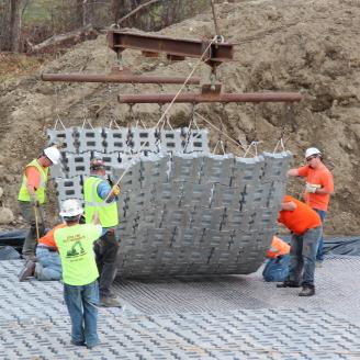 Workers laying articulated concrete blocks for a dam rehabilitation project.
