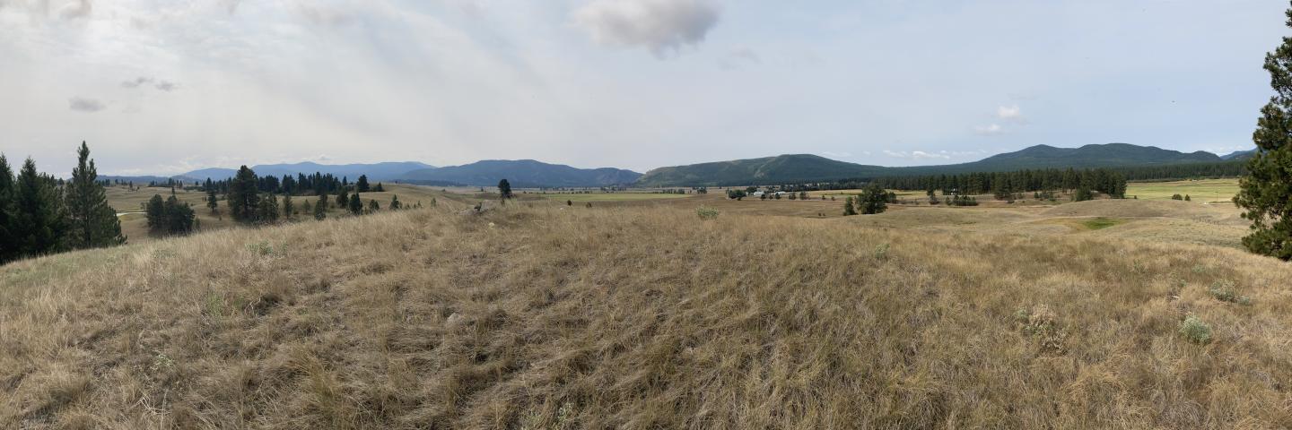Photo of the Upper Blackfoot Geographic Area which is west of the continental divide and part of the Rocky Mountain Range. The area is characterized by mostly rolling hills and mountains that are underlain by various types of rock. High peaks are topped with volcanic rocks with areas of exposed rock.